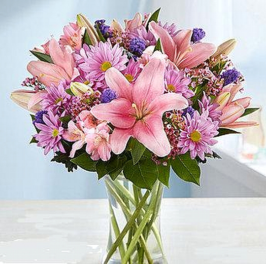 זר ורוד סגול המגיע באגרטל זכוכית.